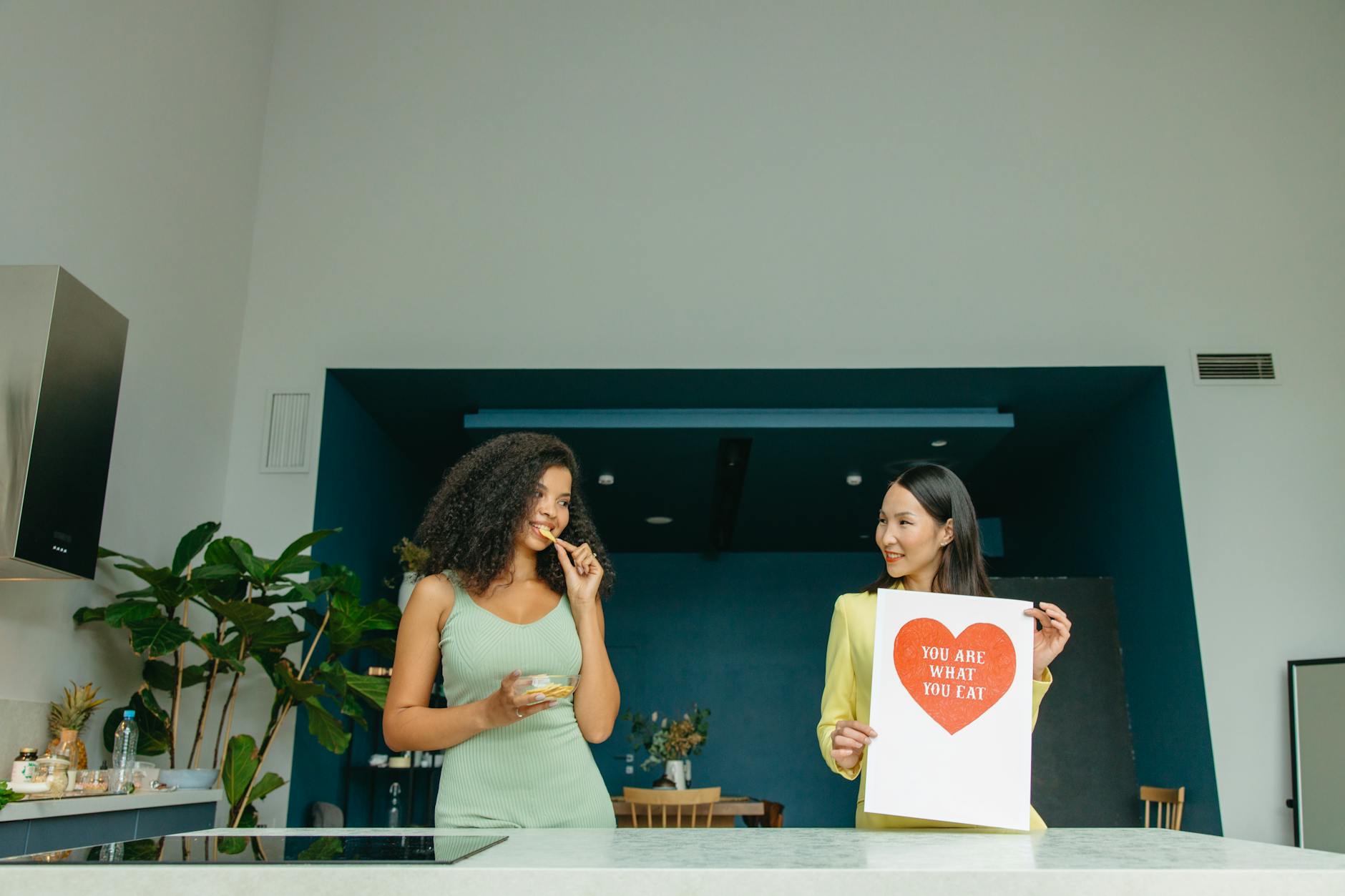 Two women enjoying healthy food and promoting nutrition awareness in a modern kitchen. (Photo by Yaroslav Shuraev on Pexels)