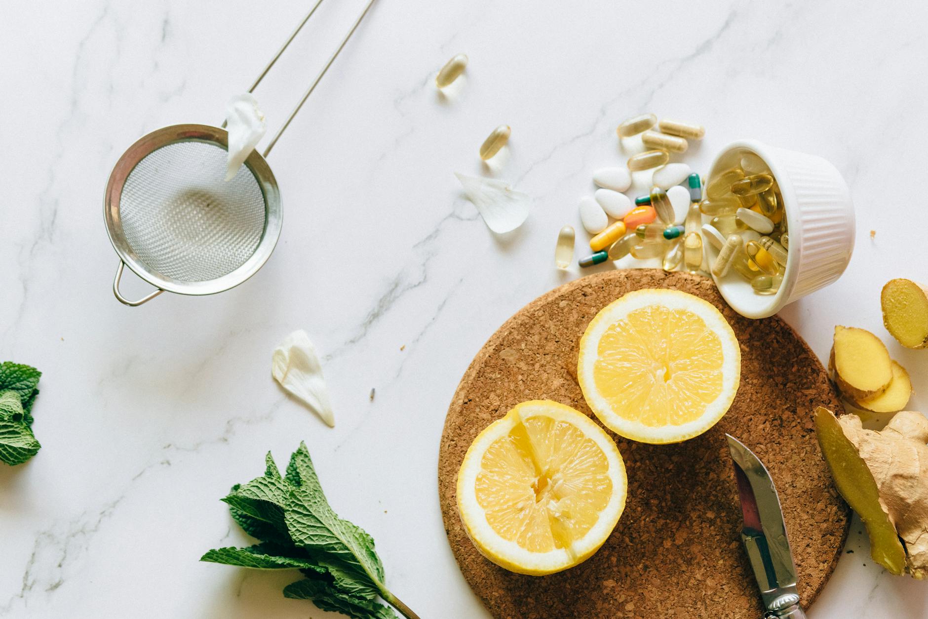 Flat lay of lemon, ginger, and supplements on a marble surface, illustrating natural remedies. (Photo by Nataliya Vaitkevich on Pexels)